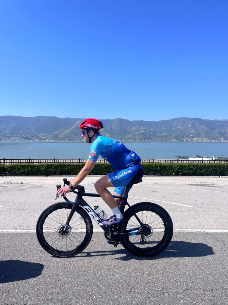 Side view of Jon riding FELT bike with lake and mountains in background