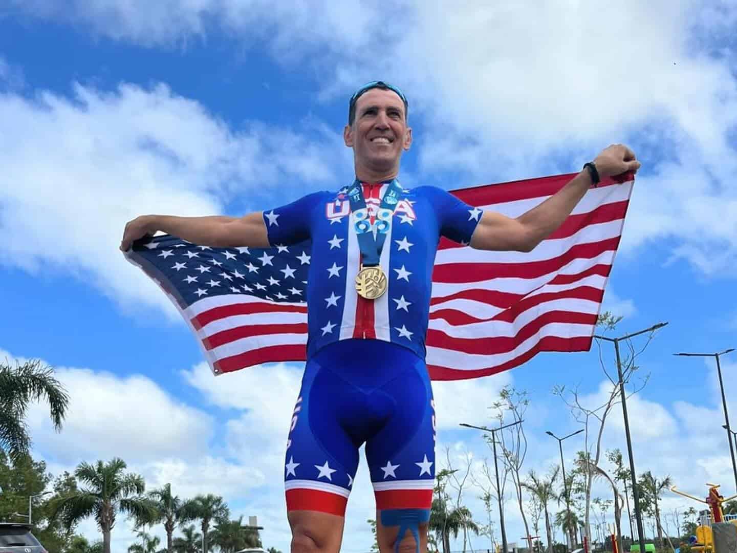 Gil Ron USA cyclist wining gold medal and standing with american flag