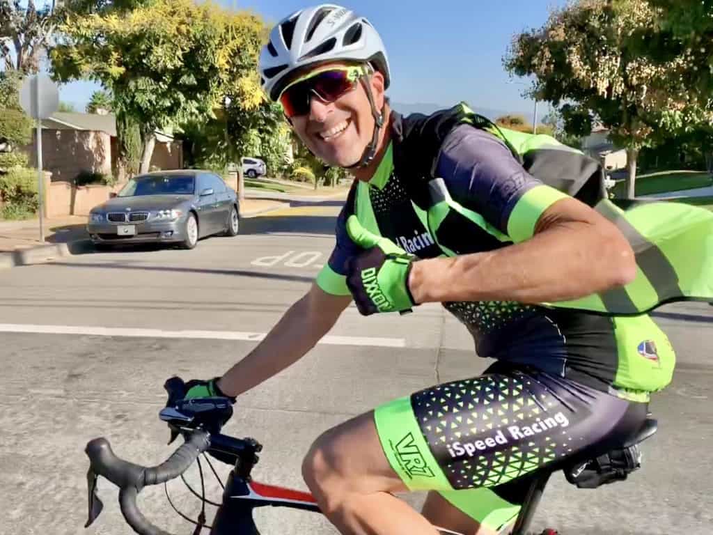 Rocky side profile on bike smiling at camera holding a thumbs up