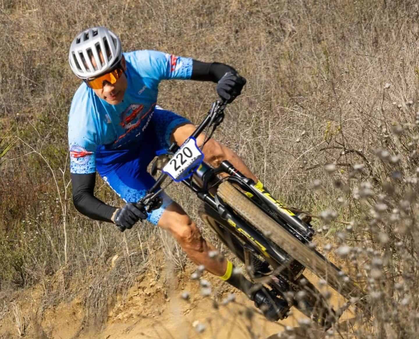 iSpeed cyclist riding on side of dirt hill in brush on mountain bike