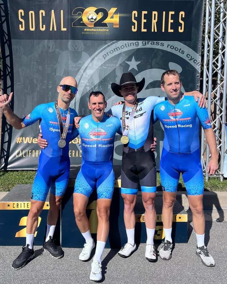 iSpeed cyclists Tamas, Gil, Brian and Jon standing in front of podium at Roger Milikan race.